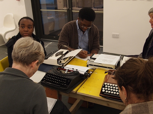 Writers working at a table with typewriters