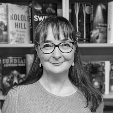 Black and white photo of Jenny Savill standing in a book store.