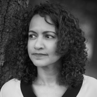 Black and white portrait photo of Sonia Faleiro standing in front of a tree.