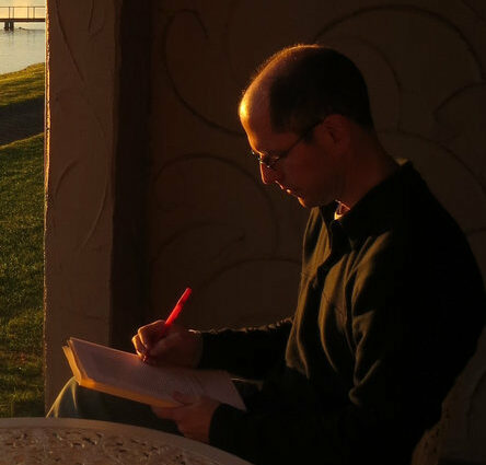 Photo of Peter Steinberg writing at a table outside